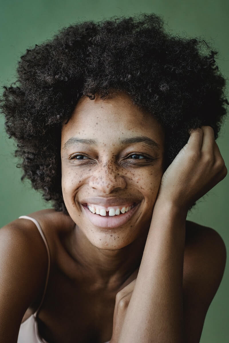 Dear Juniper : Bath + Beauty Collection - Beautiful Smilling Black Woman against rich green background
