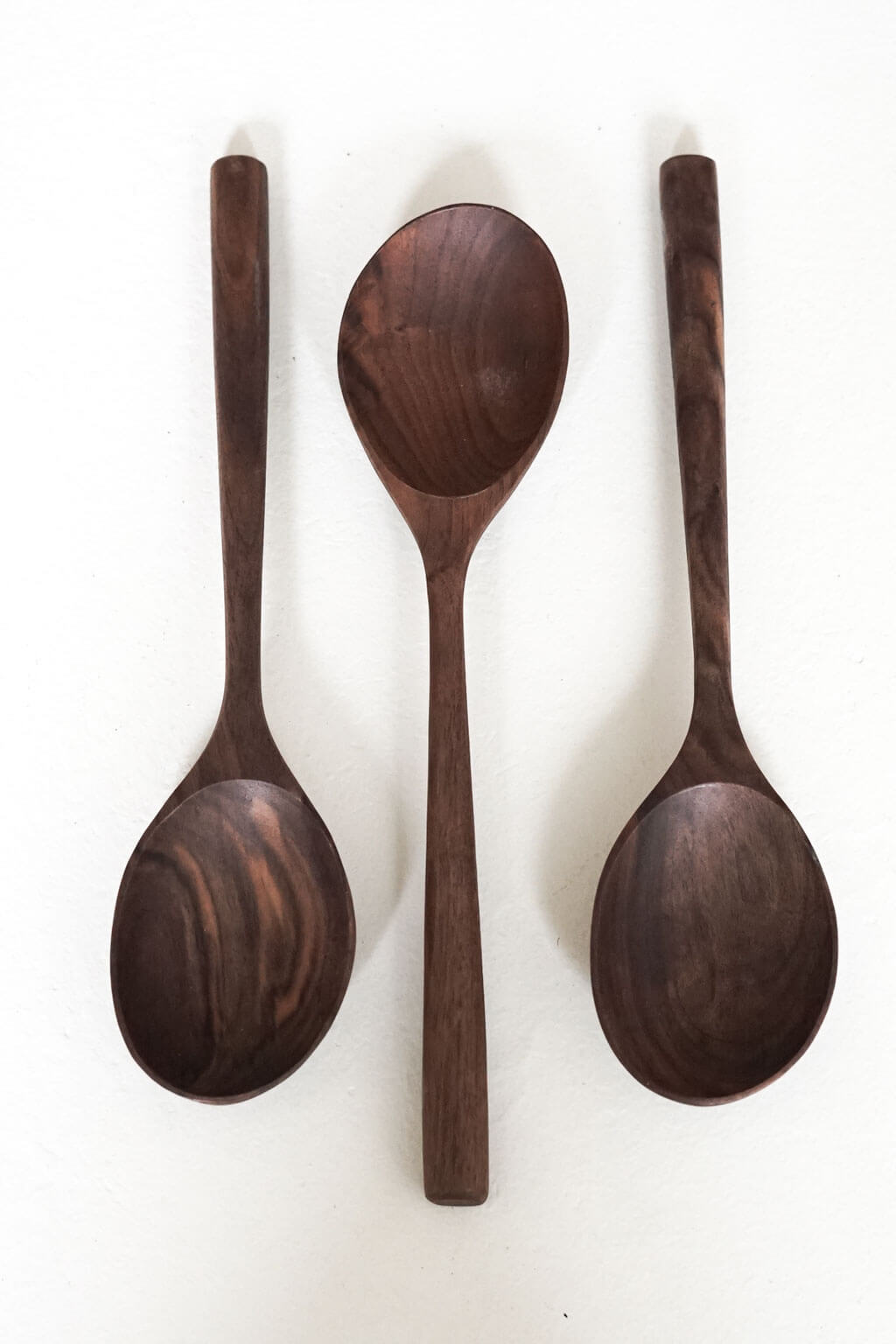 Set of three hand-carved walnut wooden spoons with varied bowl shapes and natural wood grain