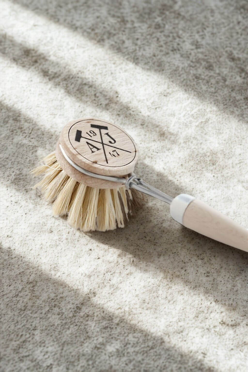 Dish brush with wooden handle and bristles on a textured surface
