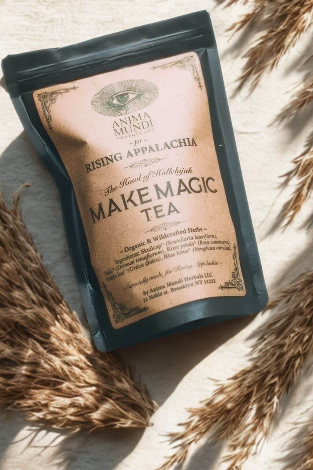 Black Tea package with 'Make Magic Tea' text on a kraft label atop a textured surface with dried grasses