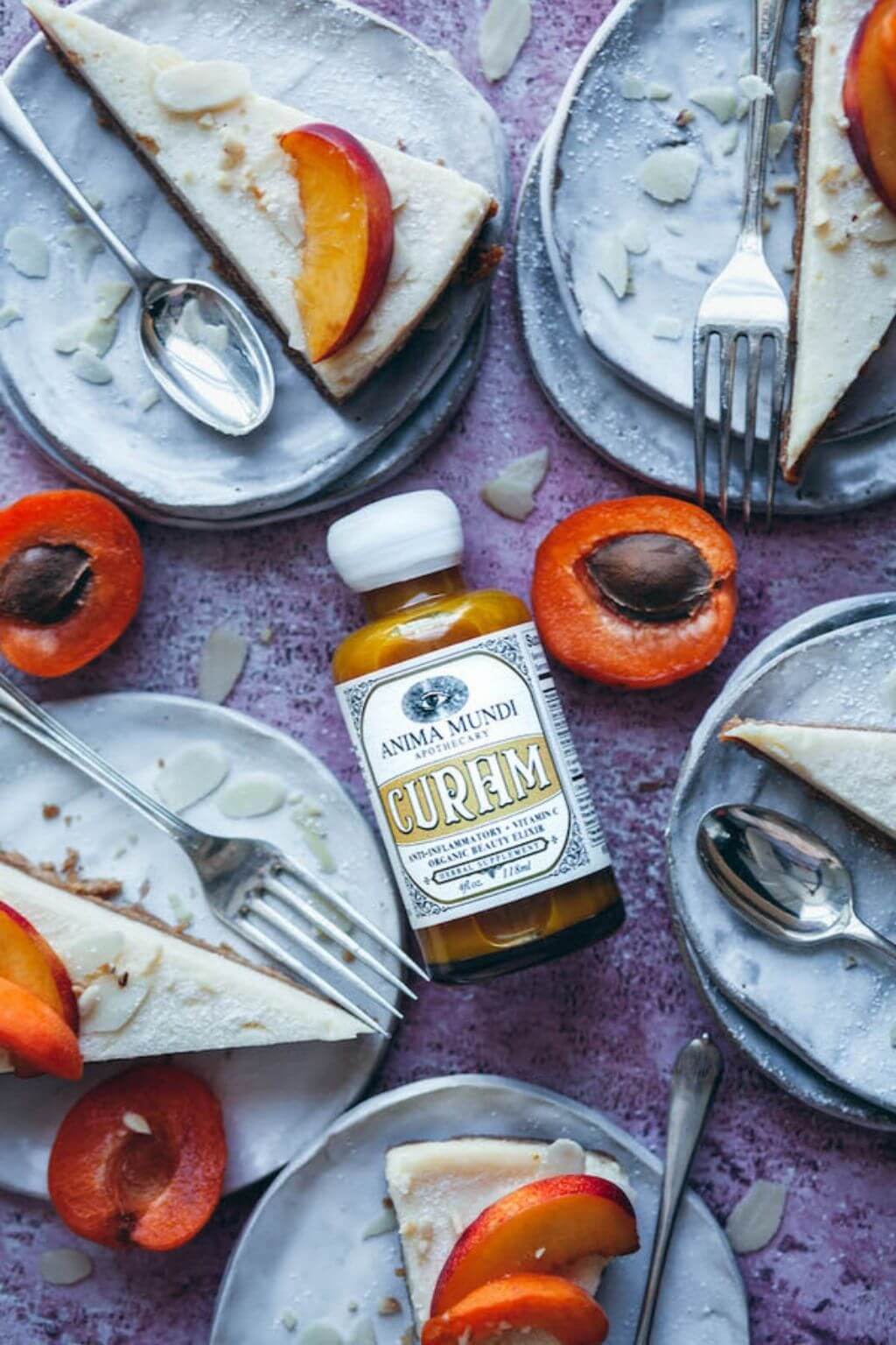 Bottle of Anima Mundi Curam with peach slices and cake on a purple surface