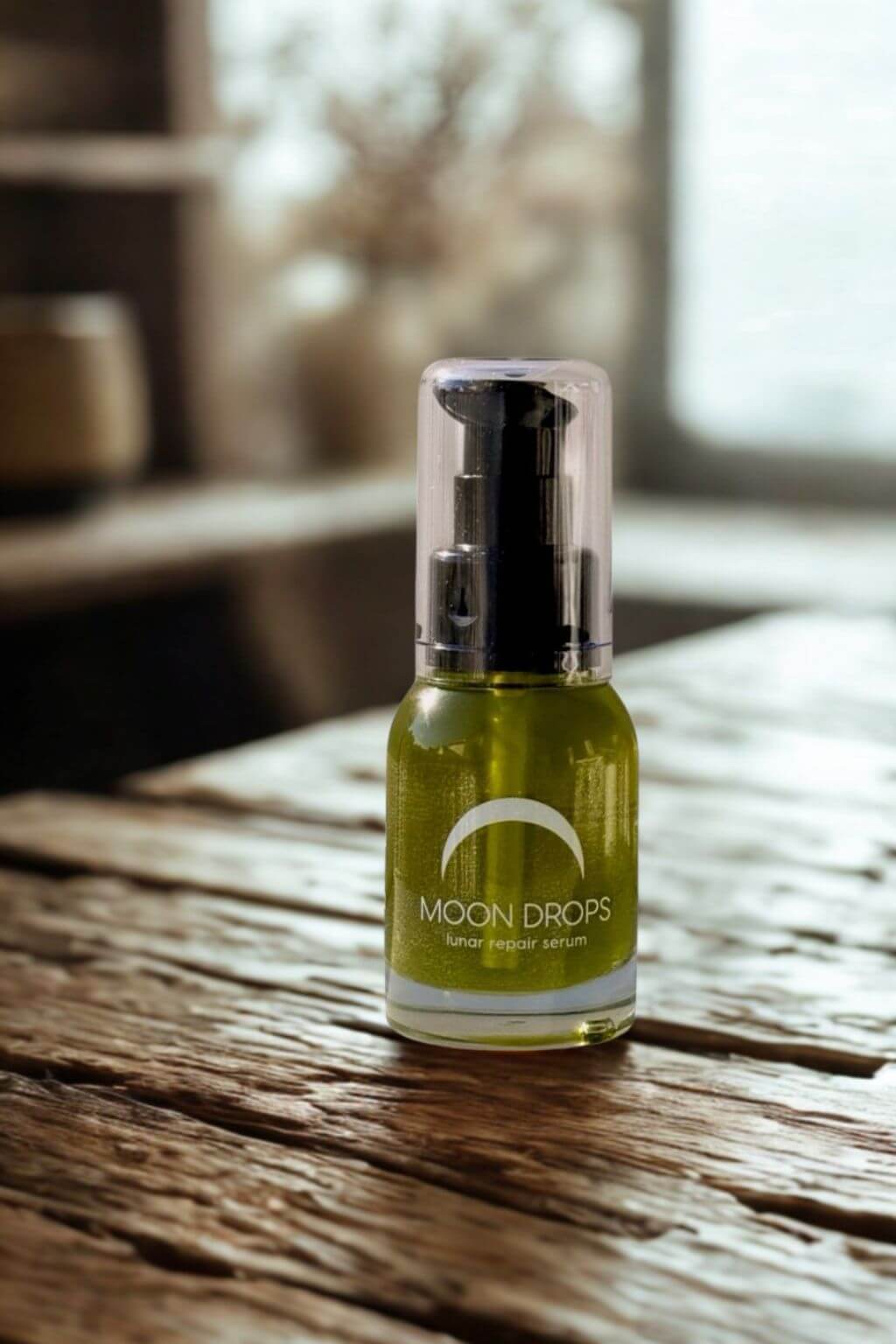 Bottle of 'Moon Drops' Serum on a wooden surface with a blurred background