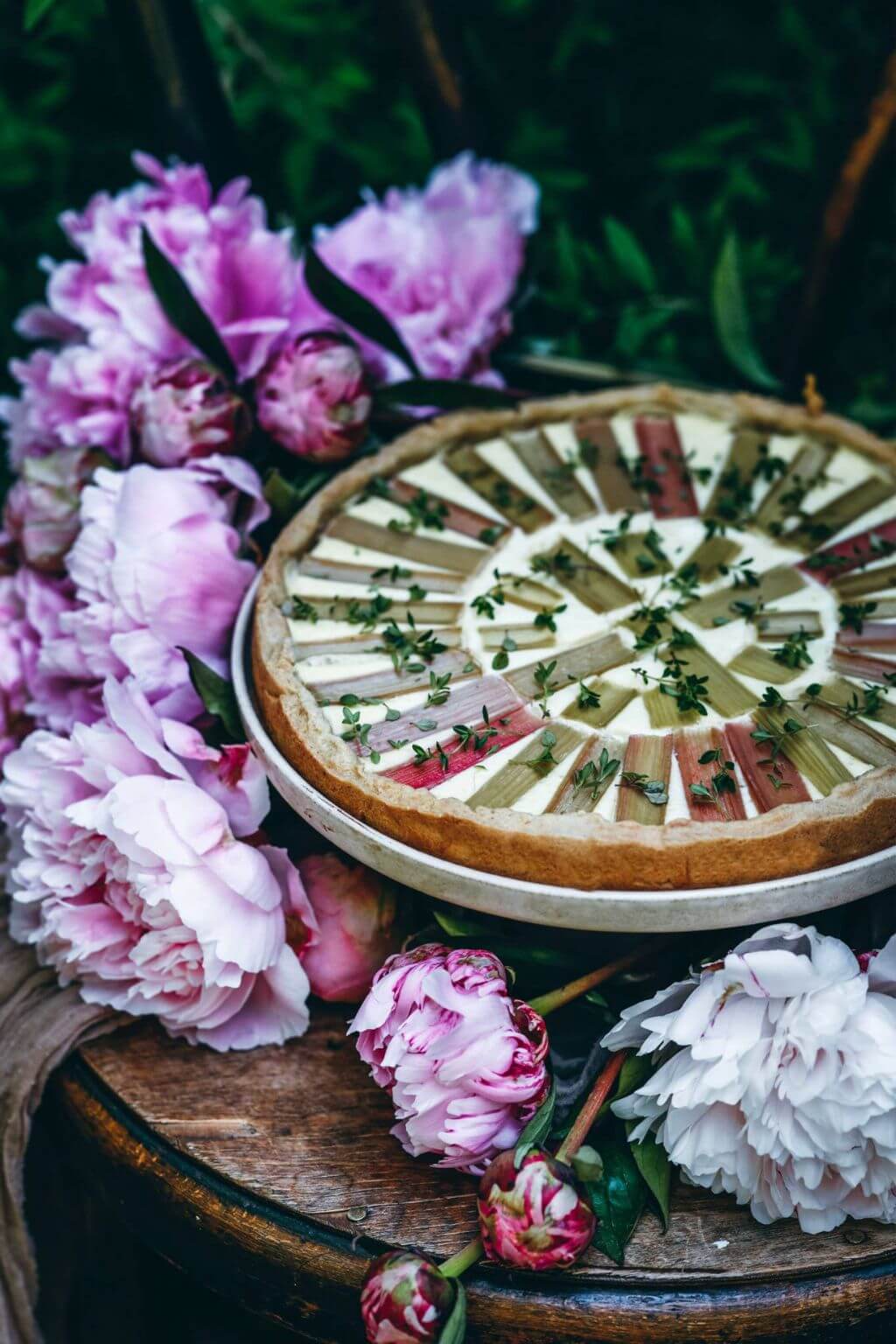 Seasonal Nordic rhubarb tart surrounded by peonies and summer flowers