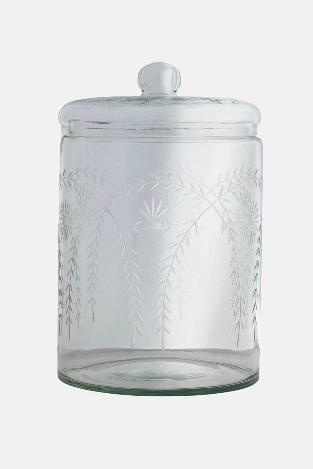 A clear glass jar with a matching glass lid and a small round knob, featuring etched botanical leaf patterns on the front, shown against a plain light gray background.