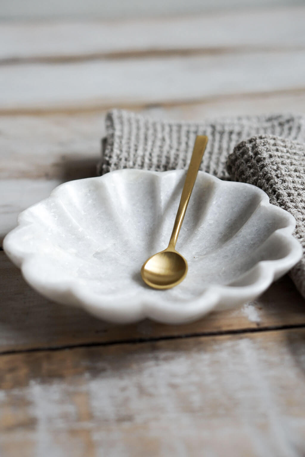 Marble dish with brass spoon styled in soft natural light