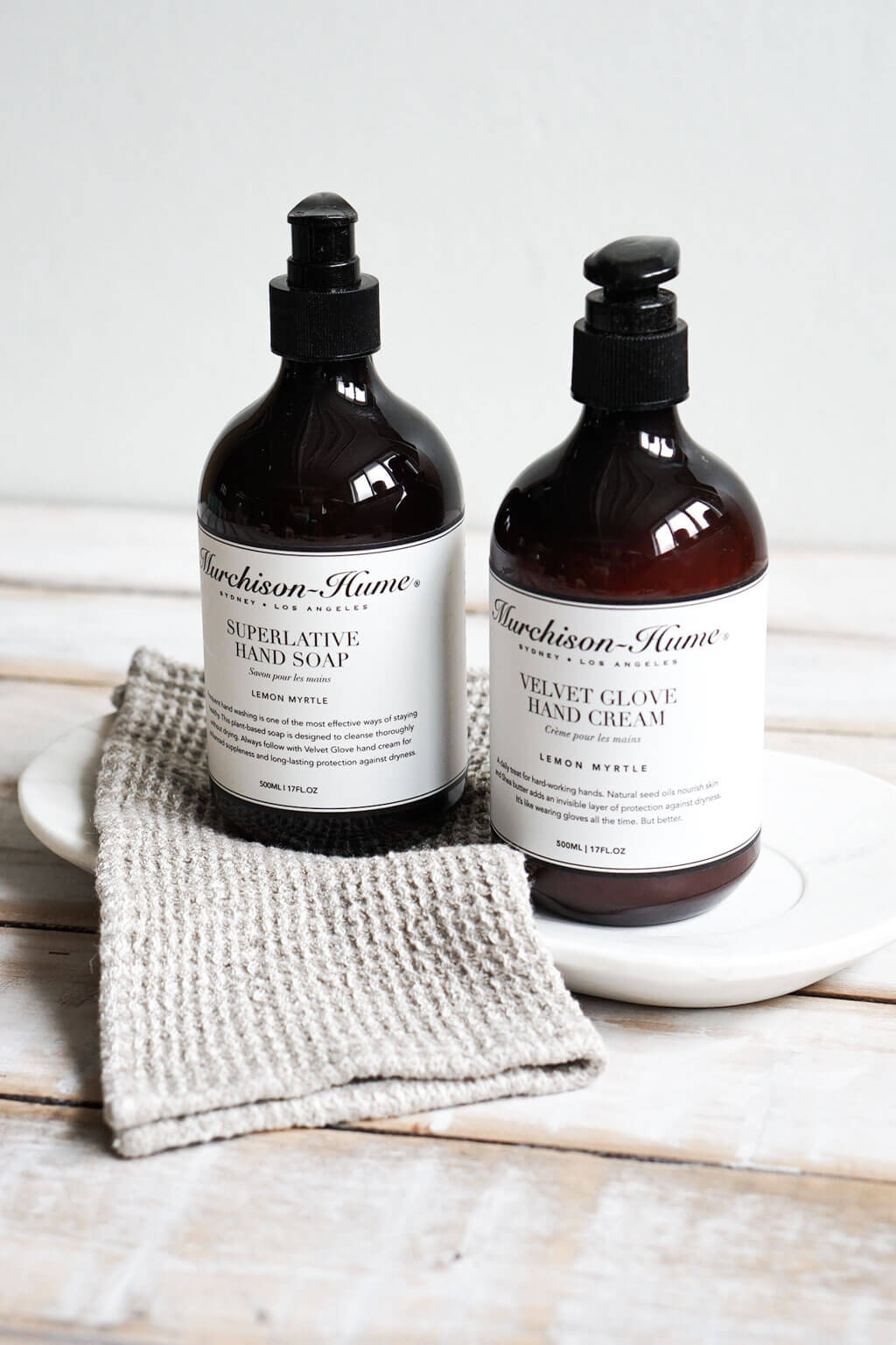 Natural linen dishcloth set styled beside amber glass home care bottles