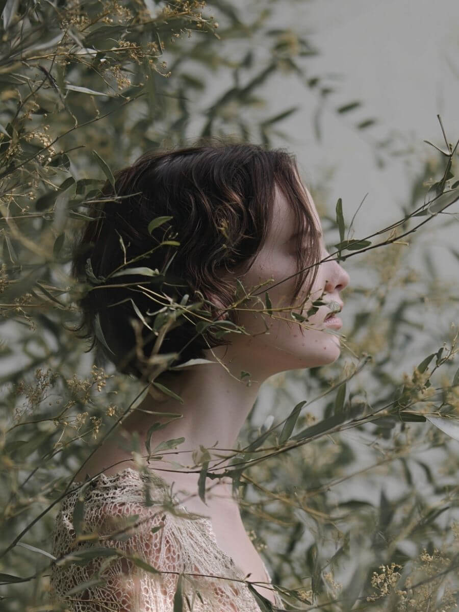Woman with short hair surrounded by greenery and flowers