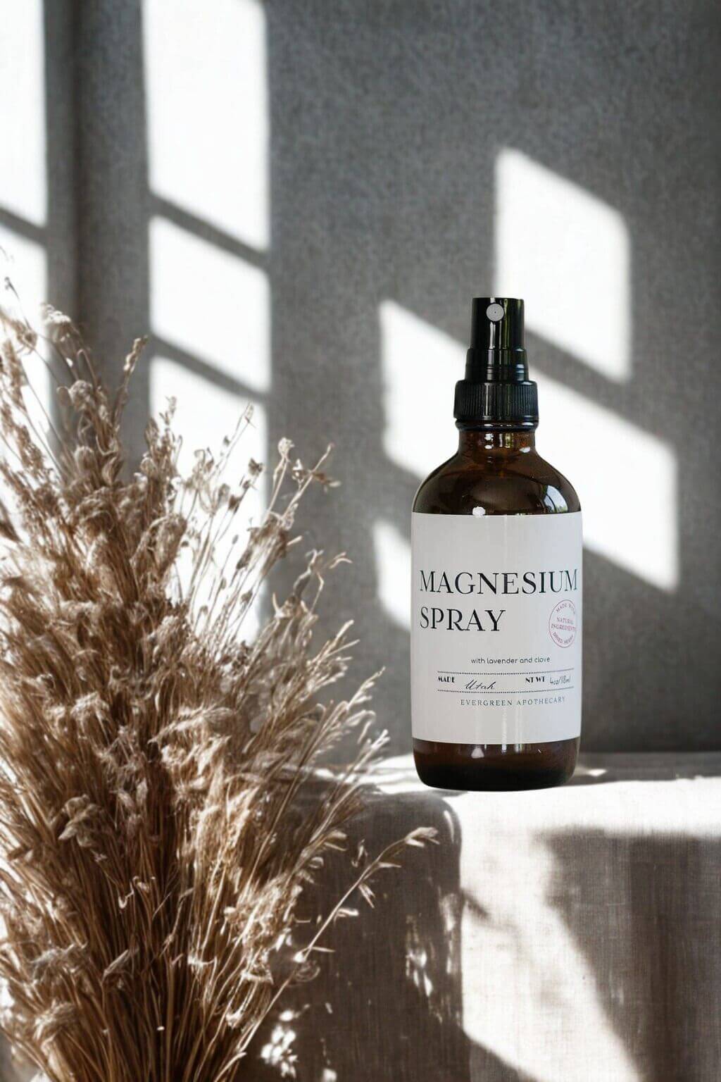 evergreen apothecary magnesium spray with dried grasses and window light shadows
