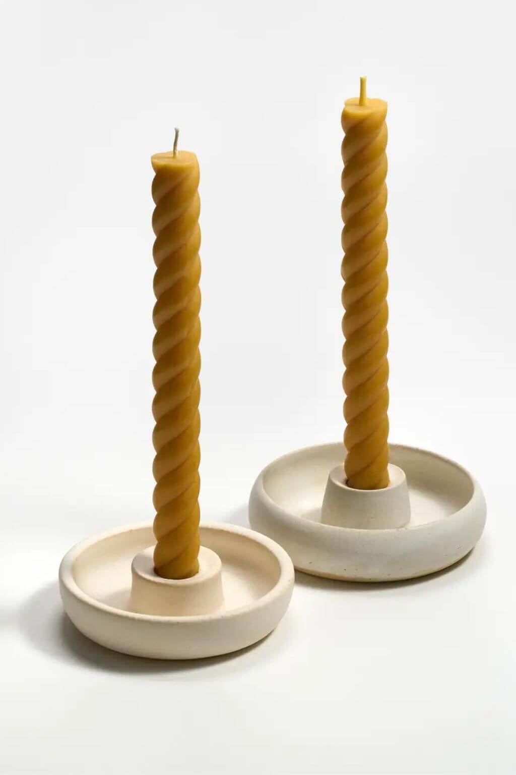 Natural yellow beeswax rope taper candles displayed in ceramic candle holders