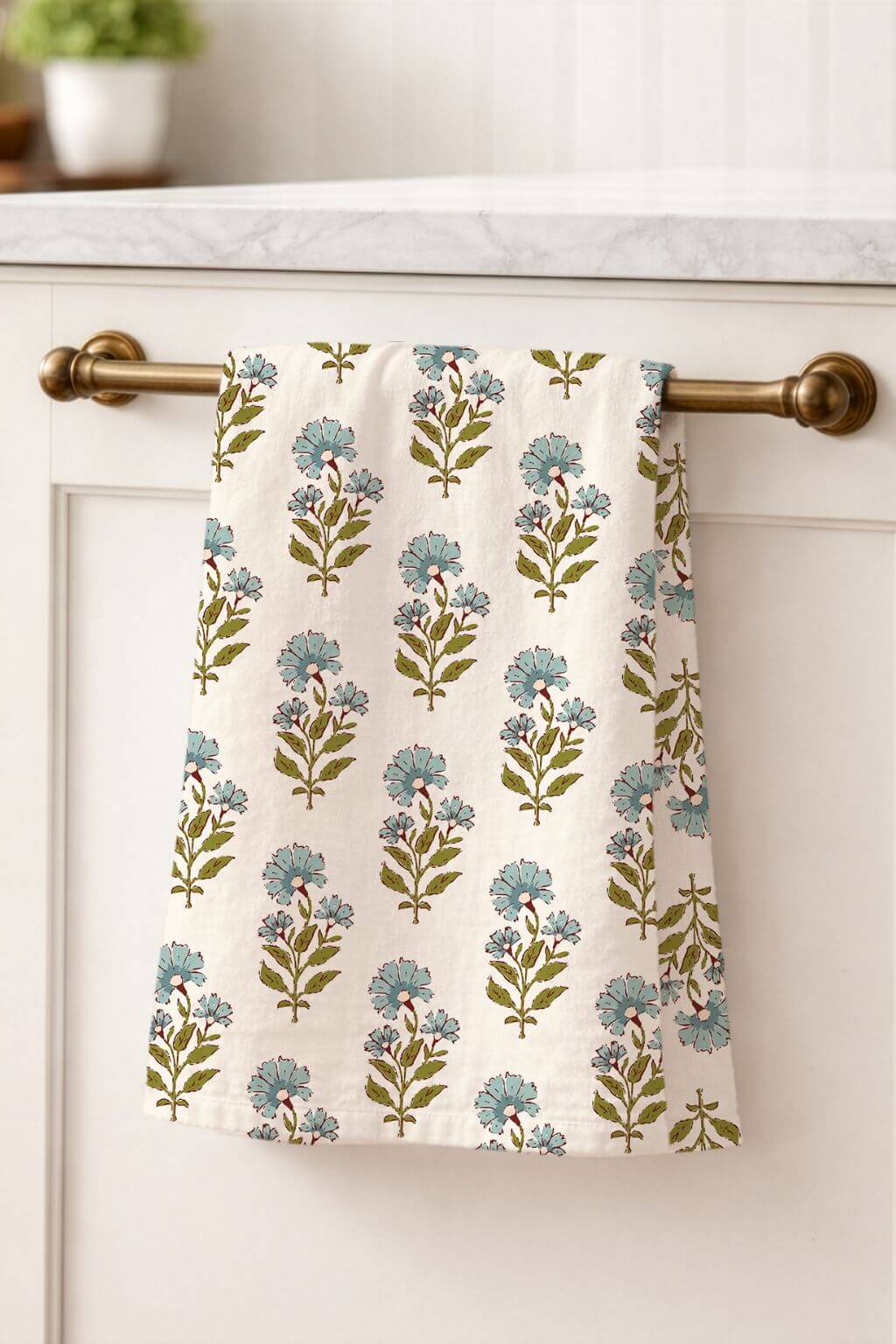 Floral patterned towel hanging on a kitchen cabinet handle.