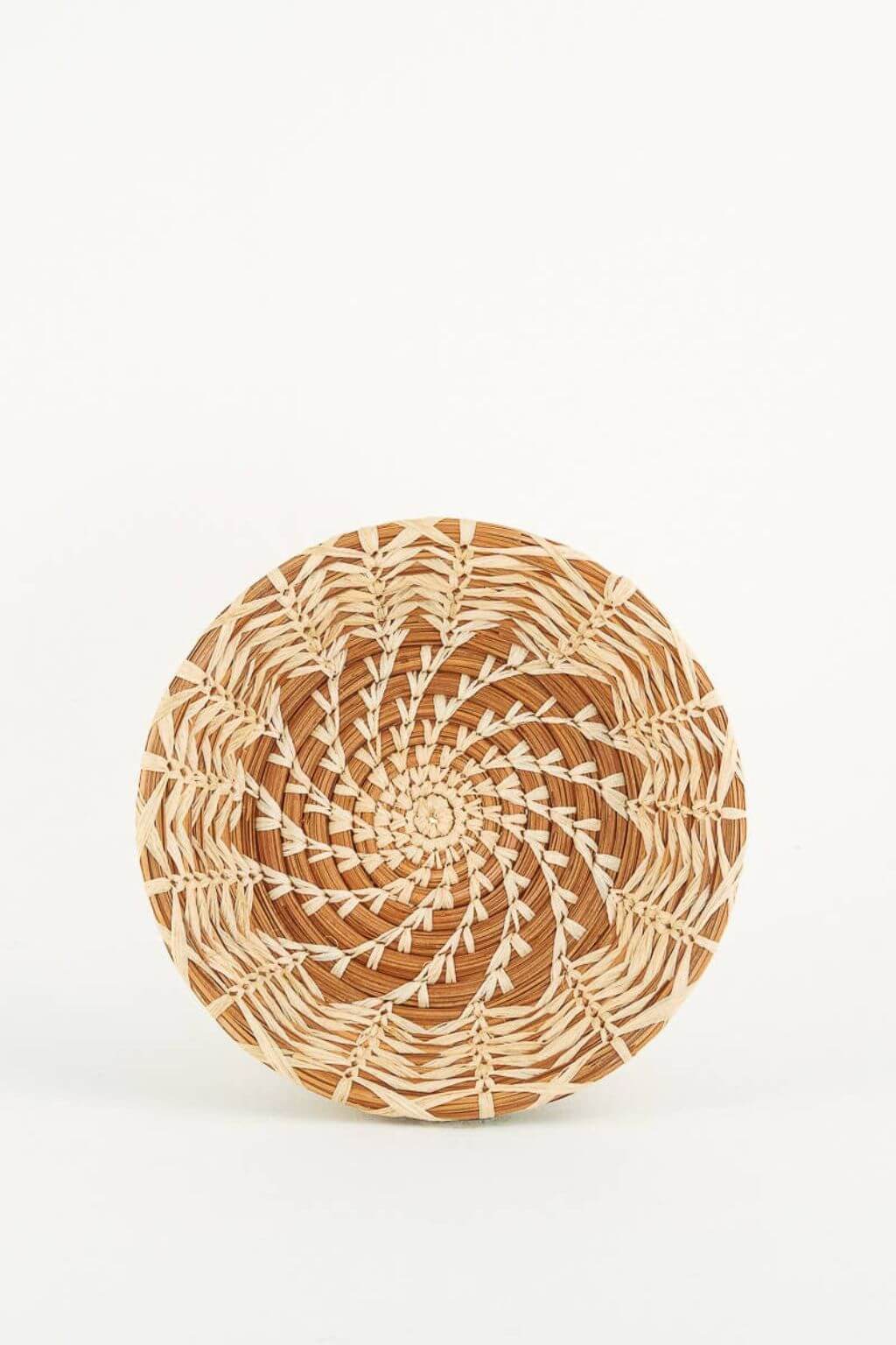 Woven basket with a spiral pattern on a white background
