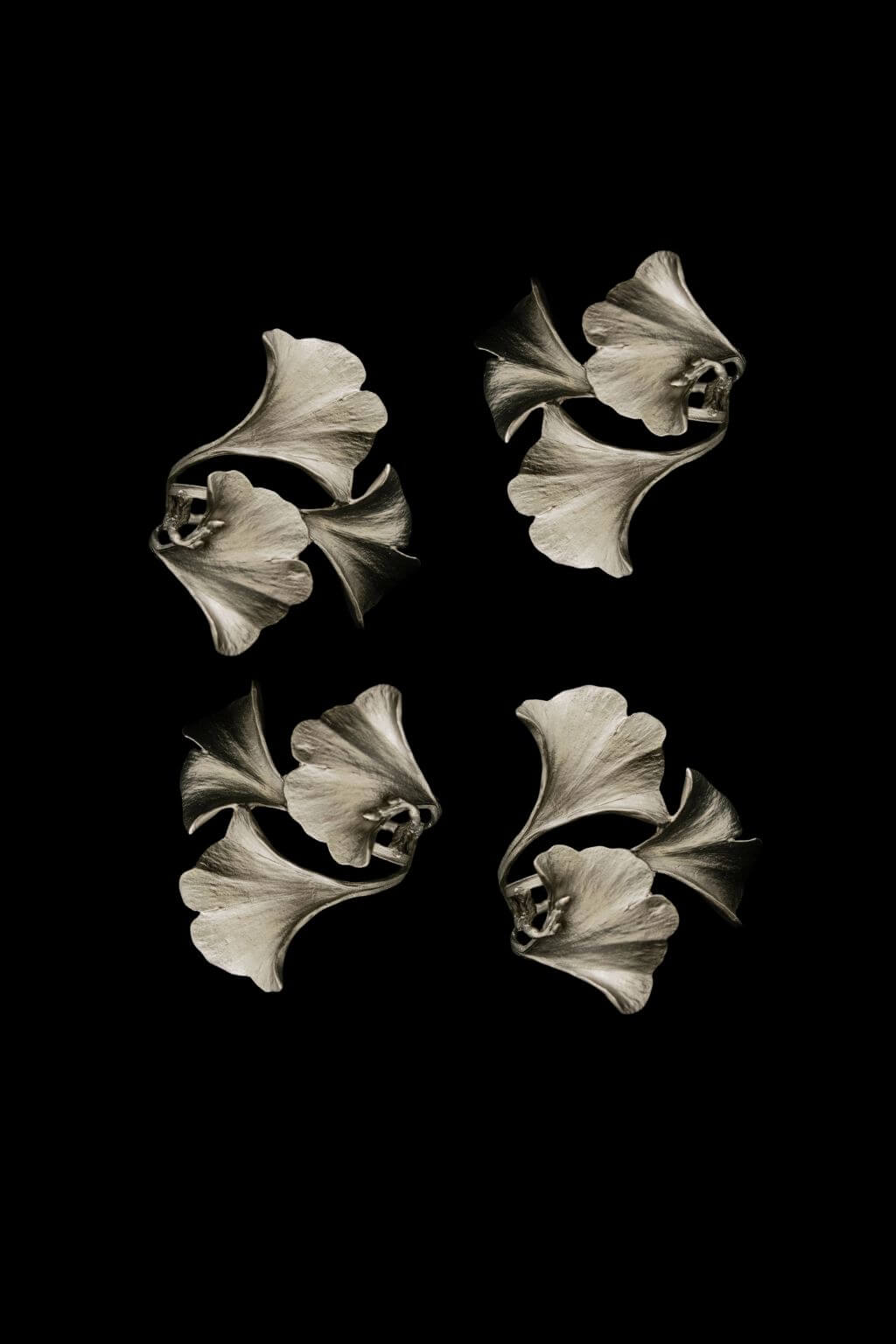 Artisan made pewter Gingko Leaf napkin rings against a black background