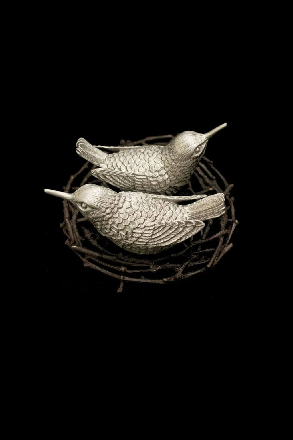 Pewter hummingbird salt and pepper shakers in twig nest tray on black background
