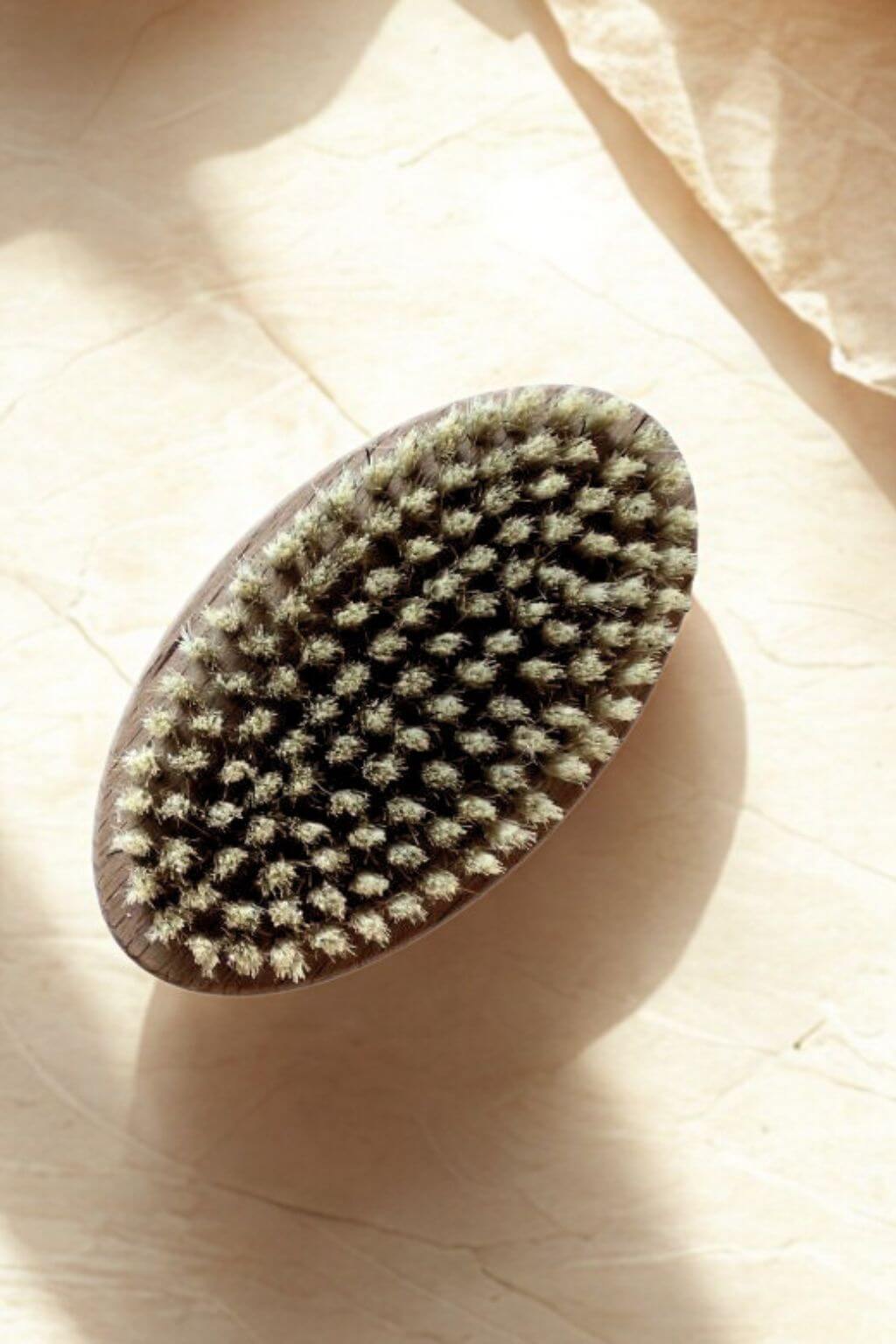 Oval-shaped brush with bristles on a light wooden surface