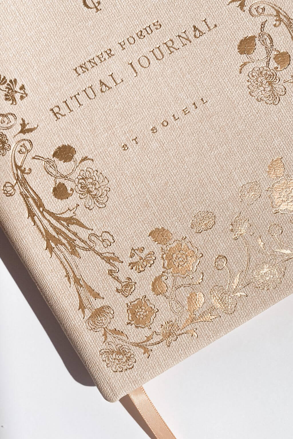 Beige journal with floral designs and 'Inner Focus Ritual Journal by Soleil' text on a white background