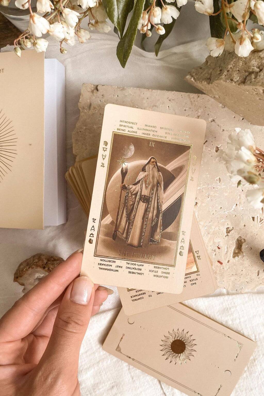 Beige Lucid Dreams tarot card held by a hand with floral and natural elements in the background