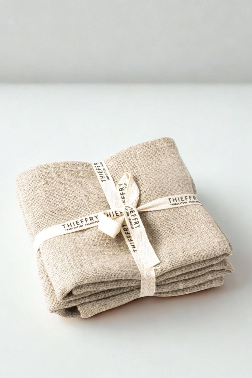 Folded textural linen towels with 'Thieffry' branding on a white background