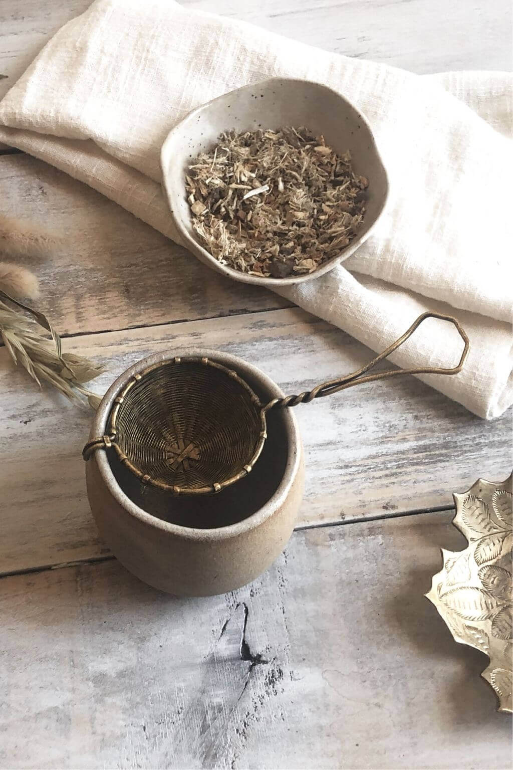 Handwoven brass tea strainer resting over a ceramic teacup