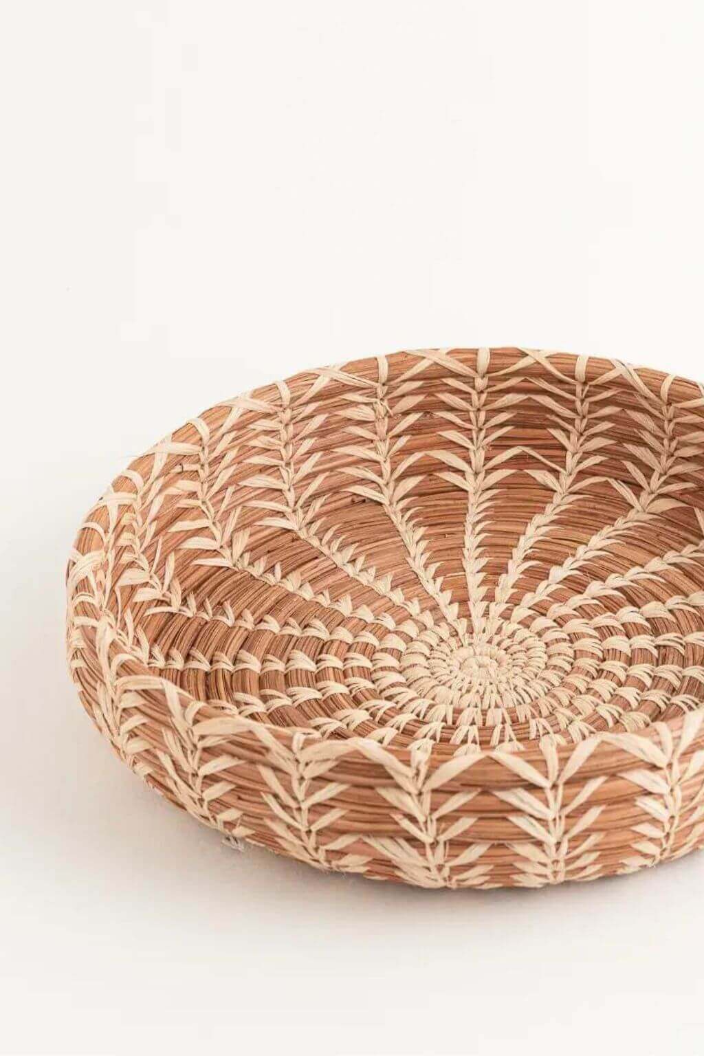 Handwoven basket made with natural pine needless in a circular design on a white background
