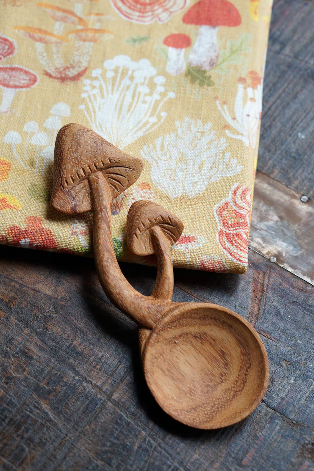 Hand-carved wooden mushroom spoon with natural wood grain on rustic surface