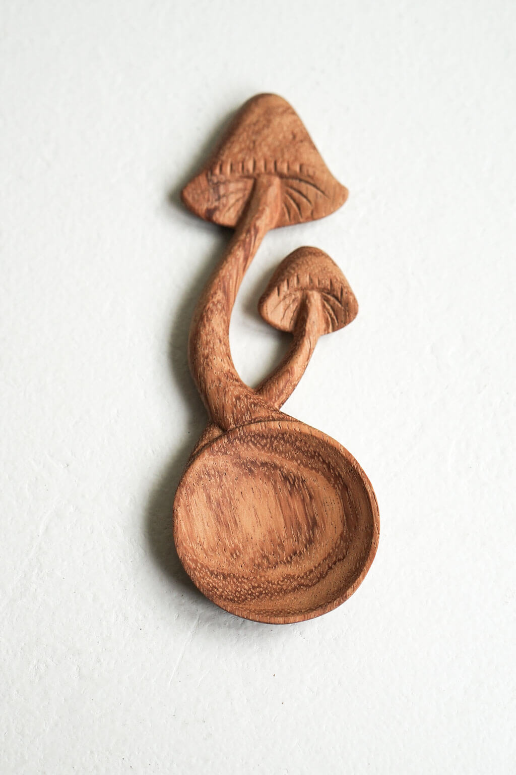 Close-up of hand-carved wooden mushroom spoon with natural wood grain detail