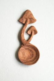 Close-up of hand-carved wooden mushroom spoon with natural wood grain detail
