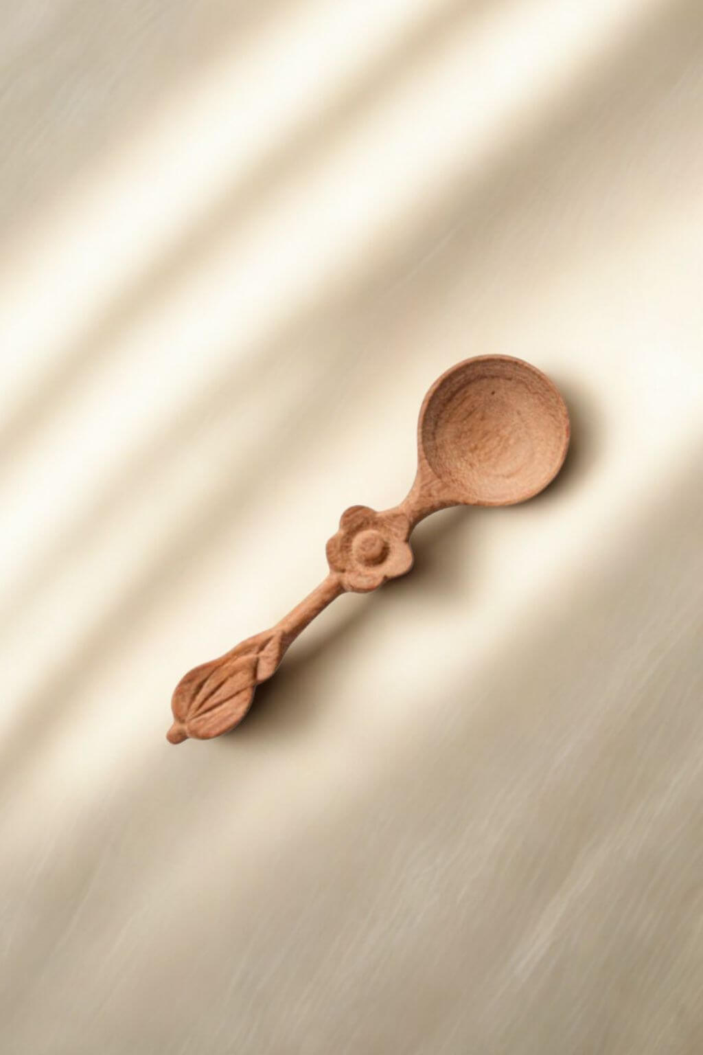 Single wooden spice spoon with floral carving in warm sunlight