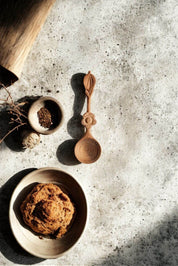 Hand-carved spice spoon styled with bowl of spices and natural kitchen setting