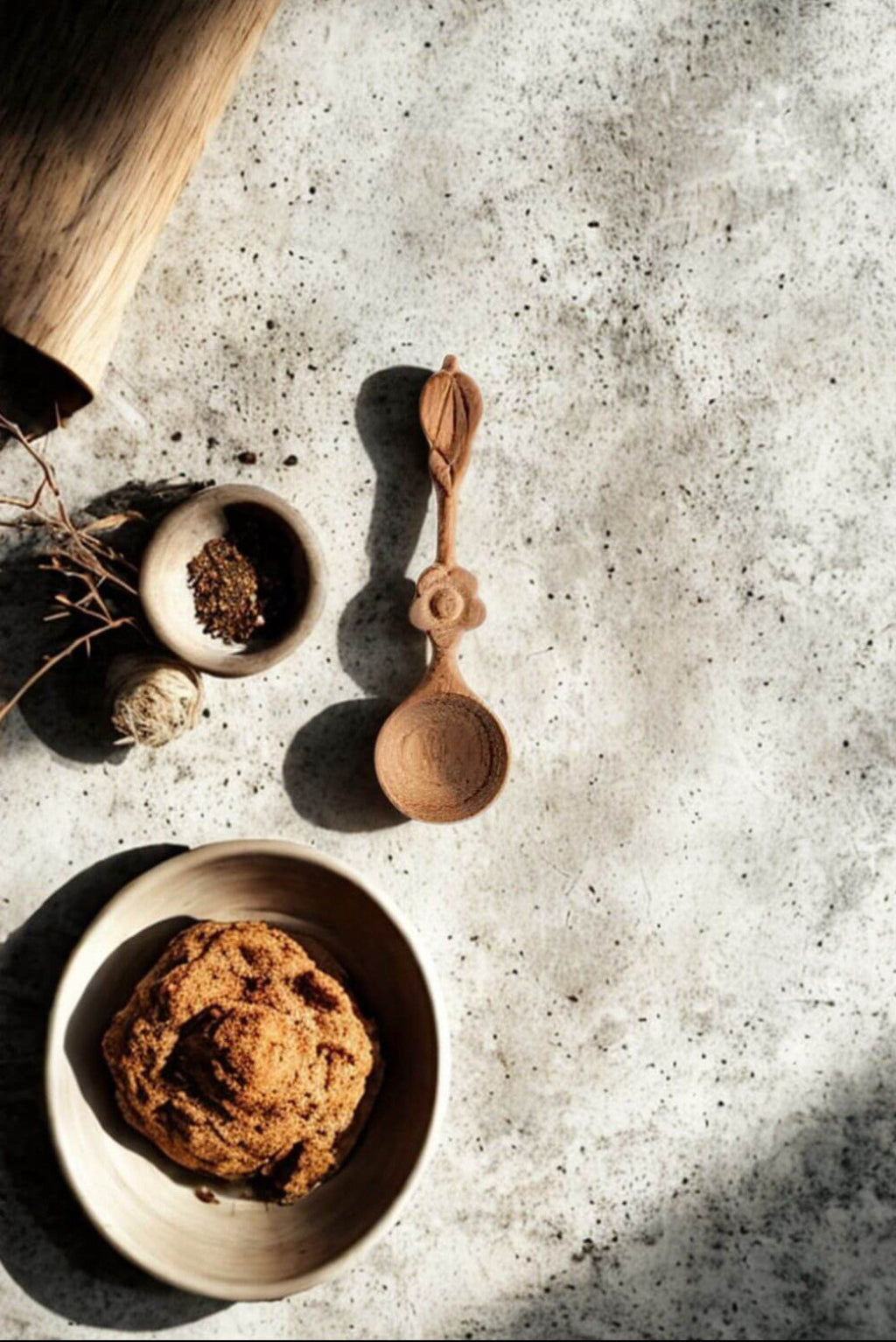 Hand-carved spice spoon styled with bowl of spices and natural kitchen setting
