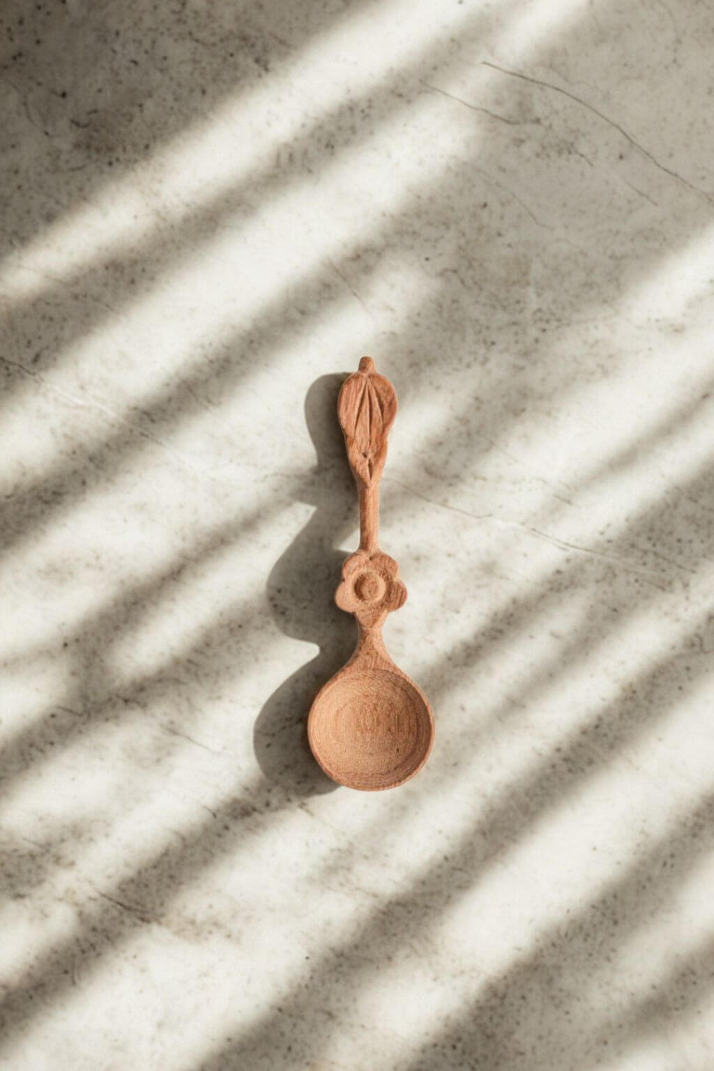Wooden spice spoon on stone surface with soft shadow and natural light