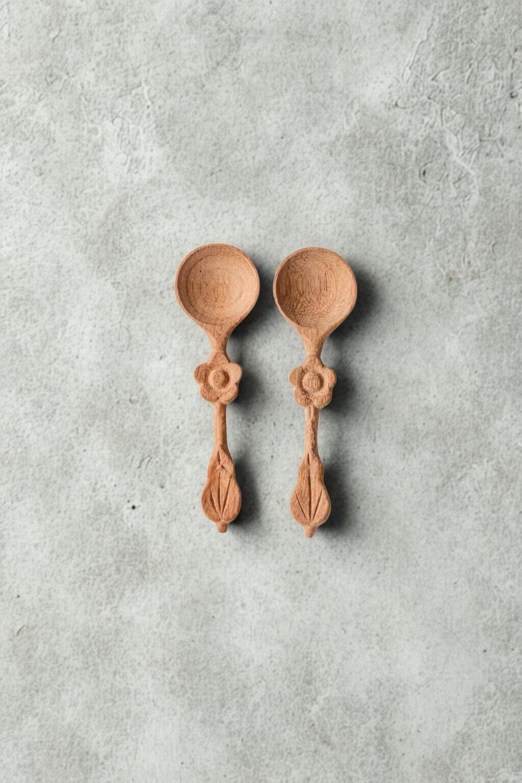 Pair of petite doussie wood spice spoons on textured neutral surface