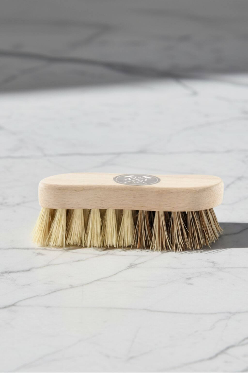 Beechwood vegetable brush on marble surface, featuring dual plant bristles for gentle scrubbing and deeper cleaning