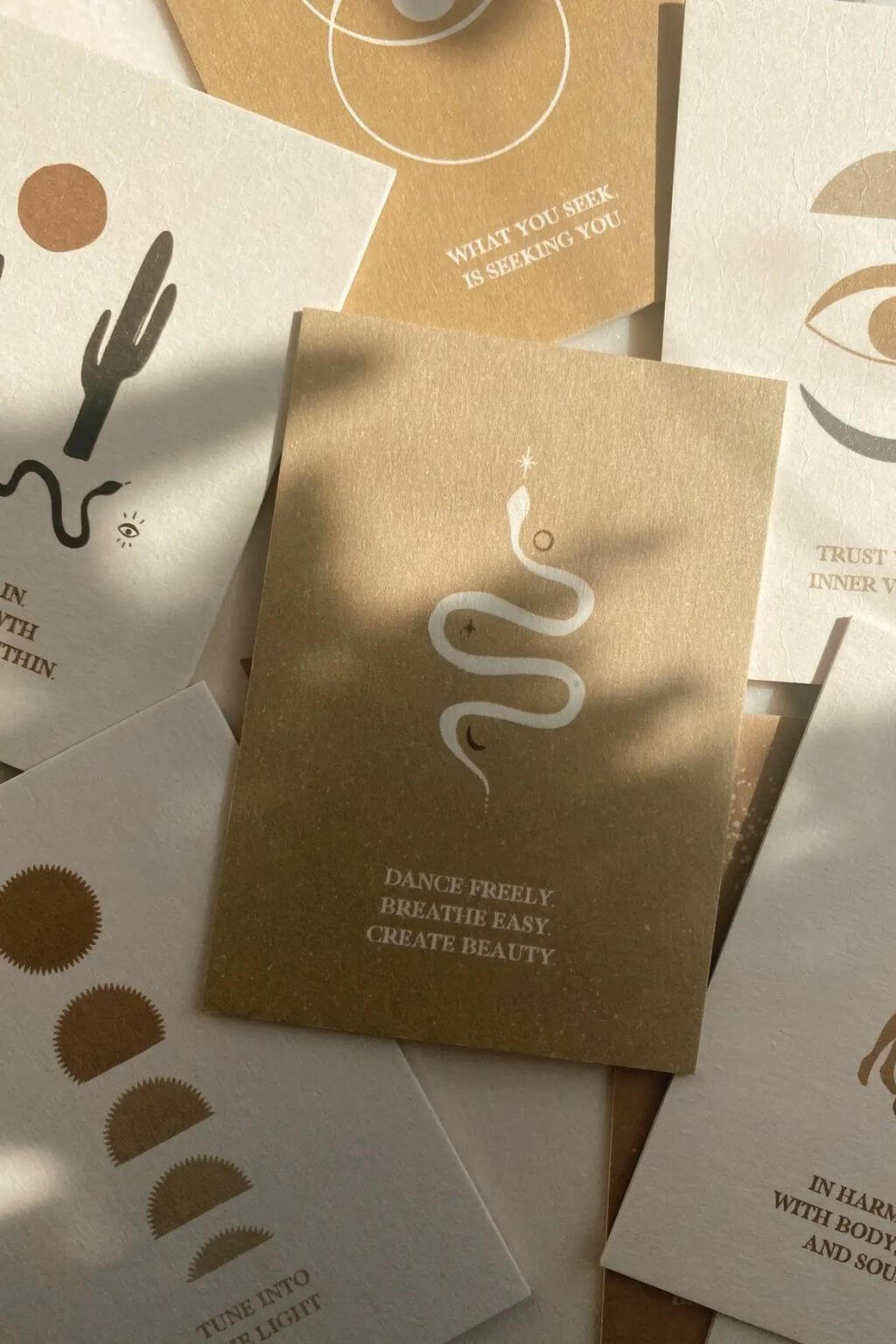 Close-up of an affirmation card reading Dance Freely, Breathe Easily, Create Beauty among earth-toned cards