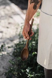 Black walnut wooden spoon held in hand outdoors