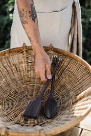 Black walnut wooden cooking utensils resting in woven basket