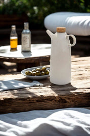 Mediterranean olive oil bottle on outdoor table with olives and oil