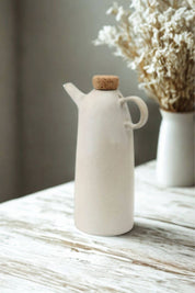 White ceramic olive oil bottle with dried flowers background