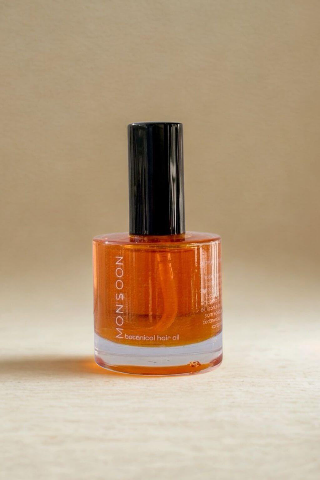 Rich orange Monsoon Botanical Hair Oil by Bhava Wellness against a beige background