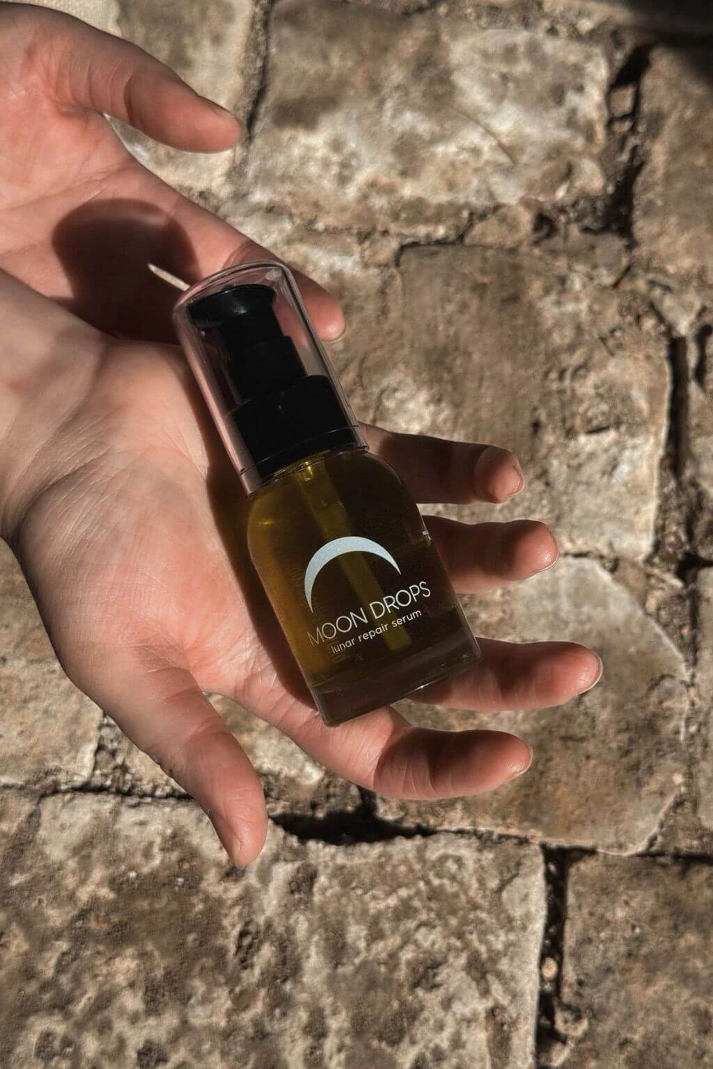 Moon Drops facial serum bottle in hand