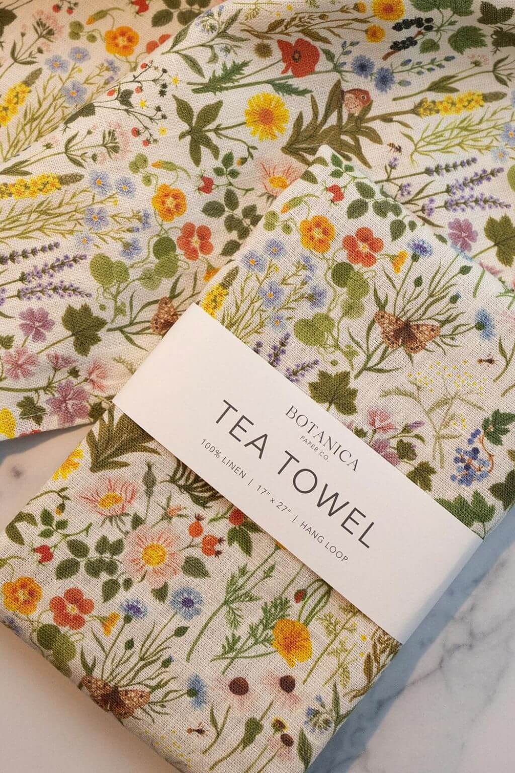 Folded Botanist Linen Tea Towel showing botanical details and colorful wildflowers.