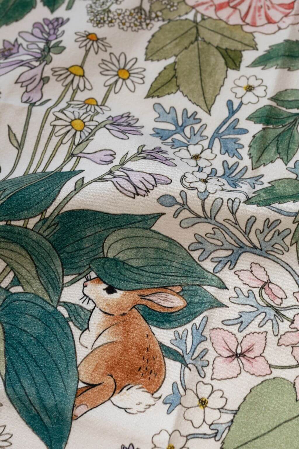 Close-up of tea towel fabric showing rabbit illustration among leaves and flowers