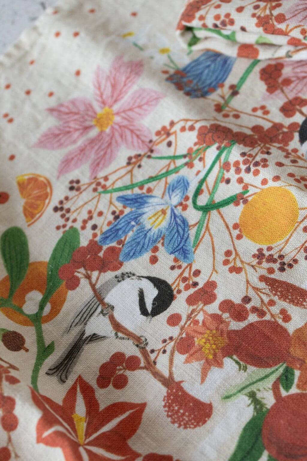 Close-up of linen fabric with hand-illustrated winter florals and songbirds.