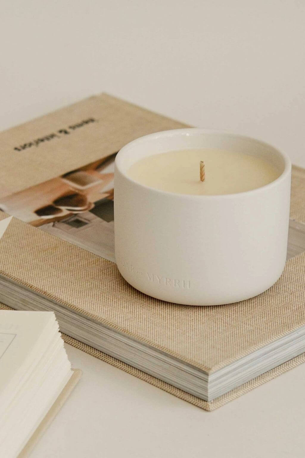 Mantra Wellness Ritual Candle resting on top of neutral-toned books, styled in a calm, minimalist setting.