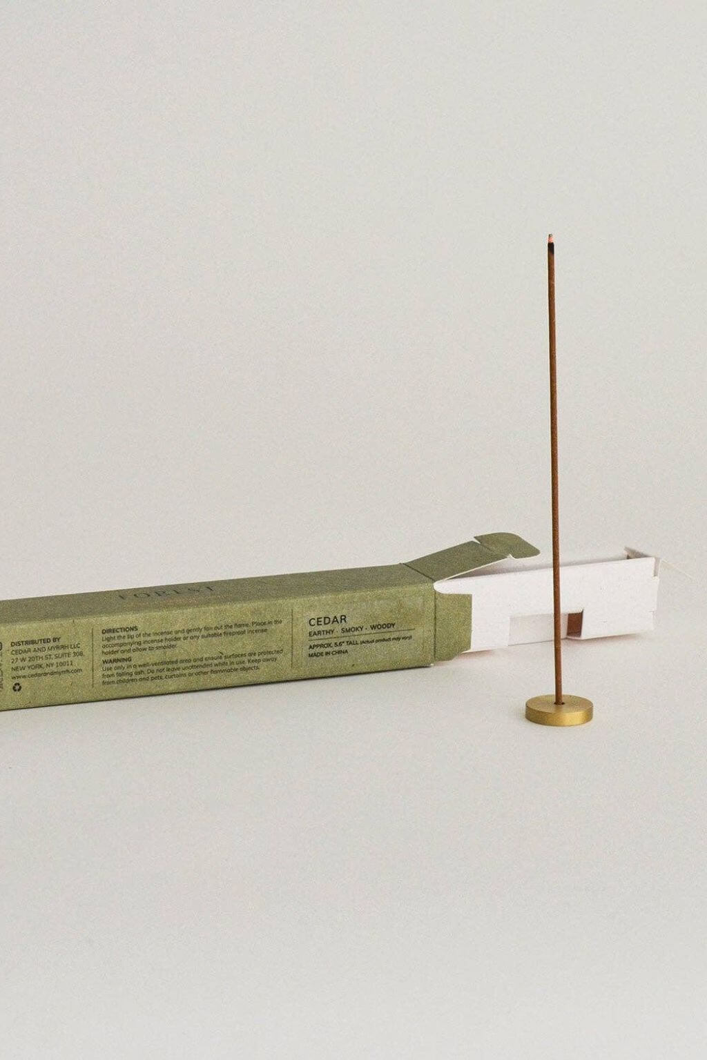 Open box of "Forest" Japanese incense sticks lying flat beside a brass incense holder, highlighting the neat arrangement of sticks inside the package.