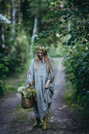 Woman gathering summer harvest along a woodland path featured in Nordic Summer Cookbook