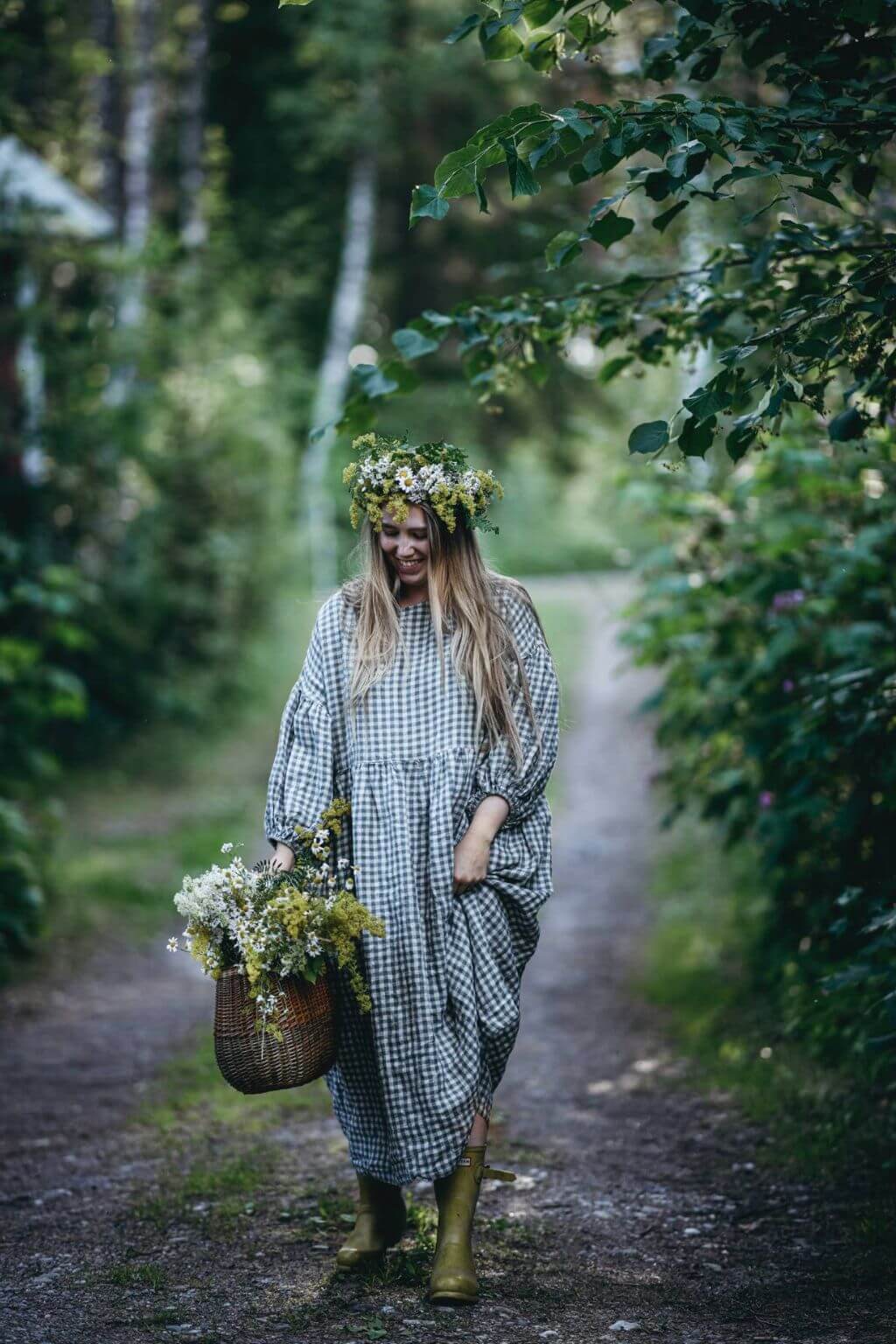 Woman gathering summer harvest along a woodland path featured in Nordic Summer Cookbook