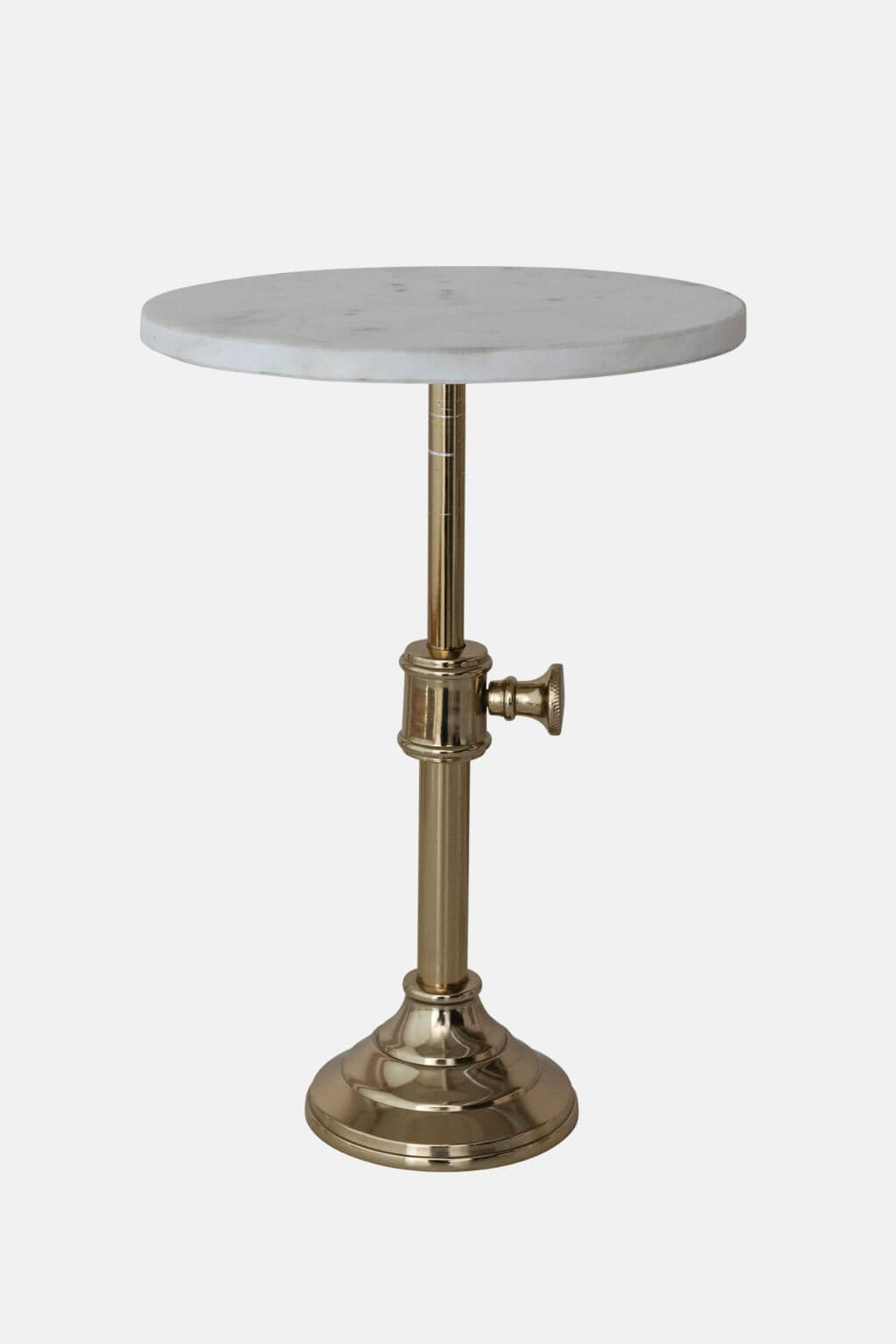 A round white marble side table with a polished brass pedestal base and a small side knob, shown against a light gray background.