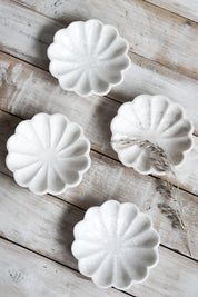 Set of four marble fluted dishes arranged on rustic wooden surface