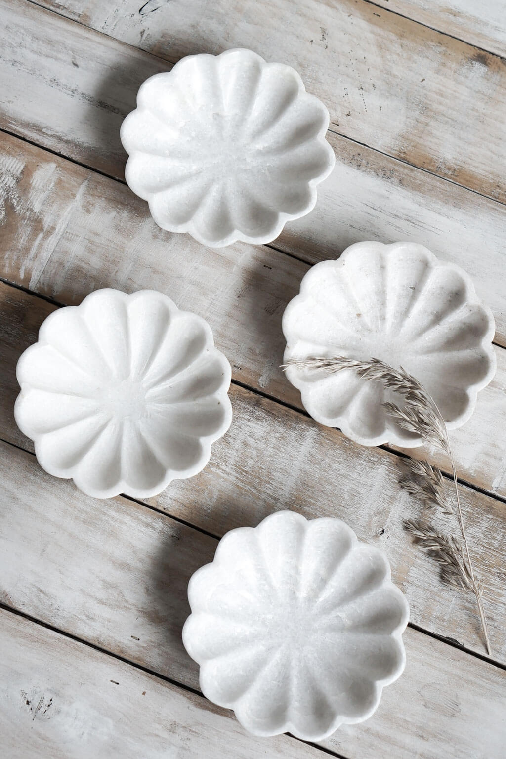 Set of four marble fluted dishes arranged on rustic wooden surface