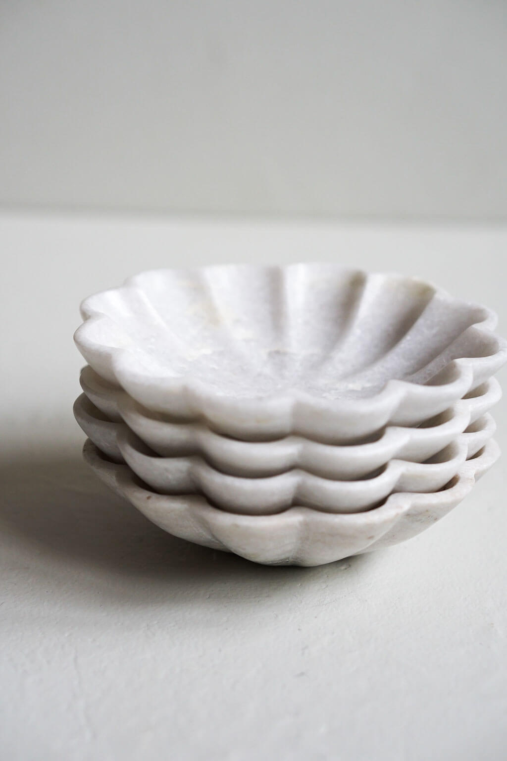 Stack of carved marble dishes showing scalloped profile and natural stone texture